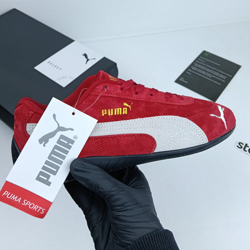 Red Puma sneaker with a tag held by a gloved hand on a light gray background