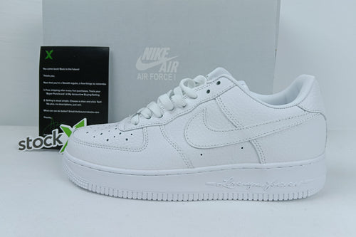 White Nike Air Force sneakers with a box and 'stockx' label in the background